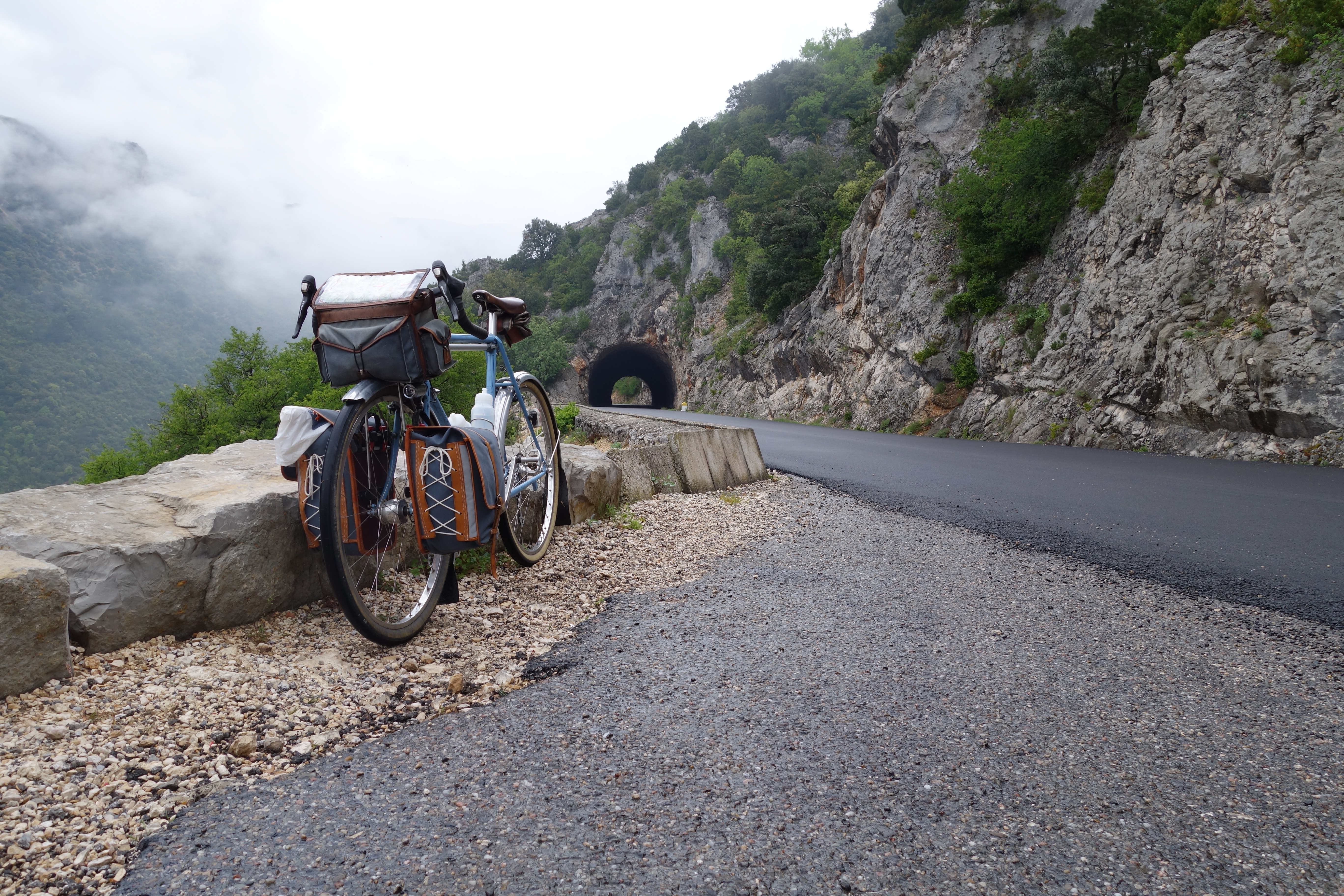 a bicycle leaning on a stone wall near a tunnel in the French countryside